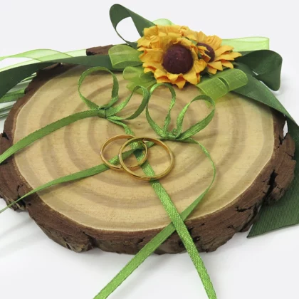 Portafedi per matrimonio fatto a mano con un disco di legno, decorato con fiori gialli e nastrini verdi in raso ai quali verranno legate le fedi.