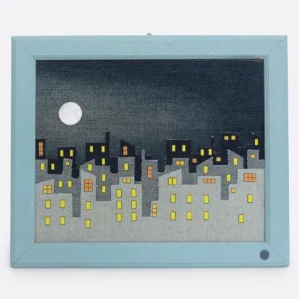 Quadro con paesaggio urbano notturno realizzato a mano con il riciclo creativo di jeans, con di cornice celeste.